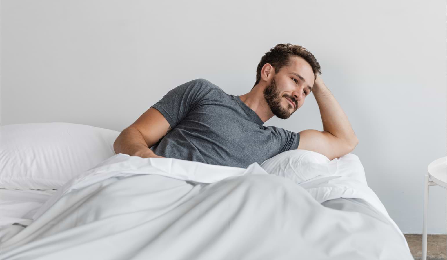 Man awake in bed under sheets
